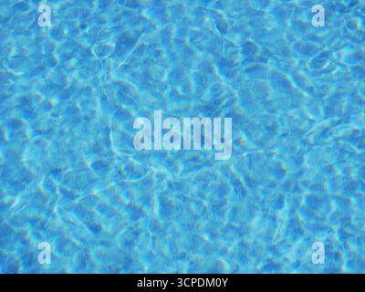 Gros plan éclatant d'une surface de piscine d'un bleu limpide avec des reflets lumineux du soleil créant des ondulations. Fond pour l'été, vacat Banque D'Images