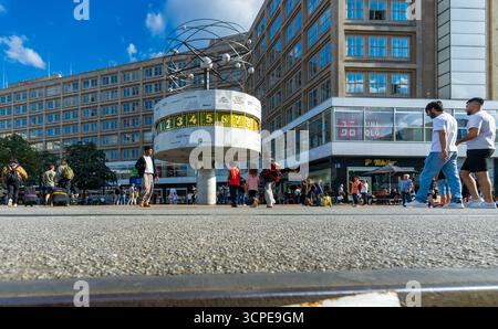 Plan grand angle bas de l'horloge mondiale (Weltzeituhr) sur Alexanderplatz avec les piétons et la vie urbaine à Berlin Mitte par une journée ensoleillée. Banque D'Images