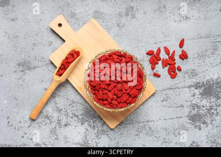 Bol et cuillère avec des baies de goji séchées sur fond grunge gris Banque D'Images
