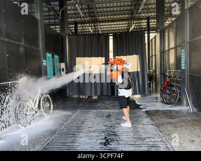Un homme couvre un vélo avec de la mousse dans un lave-auto en libre-service. Bichkek, Kirghizistan - 25 septembre 2025 Banque D'Images