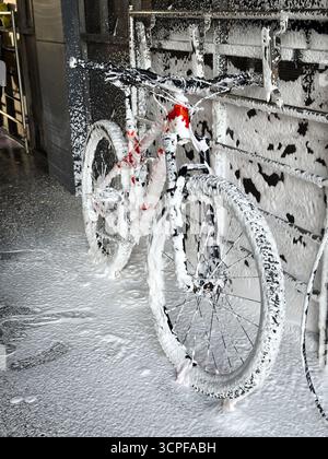 Lavage d'un vélo avec de la mousse dans un lave-auto en libre-service. Entretien du vélo. Banque D'Images