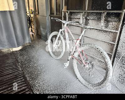Lavage d'un vélo avec de la mousse dans un lave-auto en libre-service. Entretien du vélo. Banque D'Images