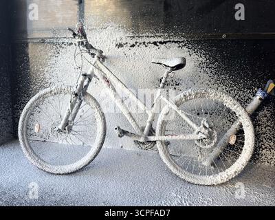 Lavage d'un vélo avec de la mousse dans un lave-auto en libre-service. Entretien du vélo. Banque D'Images