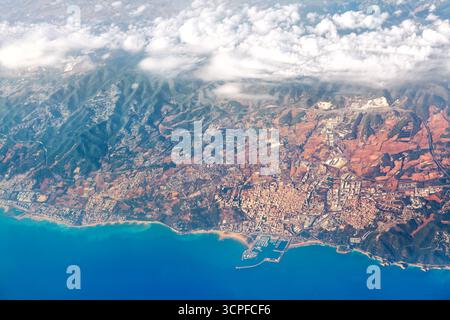 La photo aérienne montre la ville côtière vibrante nichée contre les montagnes escarpées avec la mer bleue contre le développement urbain et les nuages lointains. Natural et man-M. Banque D'Images