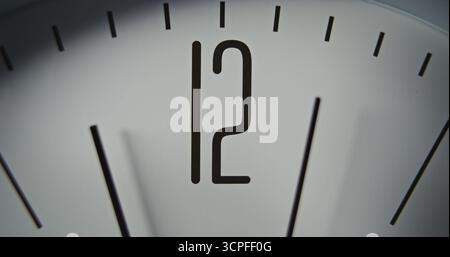 Gros plan macro de l'horloge murale minimaliste avec le numéro 12 sur le cadran et les aiguilles des secondes et des minutes. Élément de design moderne de l'intérieur. Concept de temps, ponctualité, attente, gestion du temps. Banque D'Images