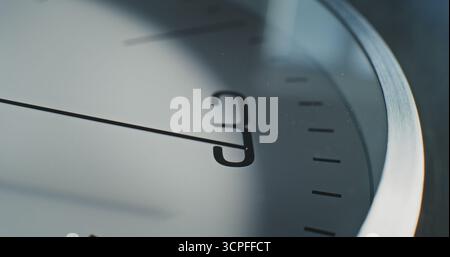 Macro gros plan de l'horloge murale minimaliste avec le numéro 12 sur le cadran et la seconde main en cours d'exécution. Élément de design moderne de l'intérieur. Concept de temps, ponctualité, attente, gestion du temps et style de vie Banque D'Images