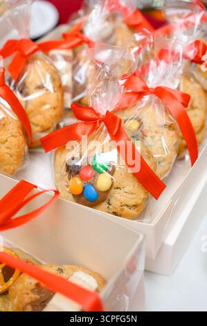 Gros plan de coffrets cadeaux avec des biscuits aux pépites de chocolat. Biscuits frais avec des bonbons au chocolat colorés, emballés dans des sacs transparents et attachés avec des rubans rouges Banque D'Images