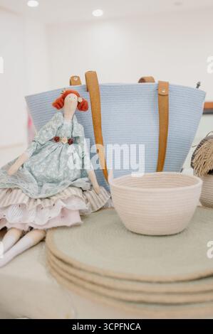 Un ensemble de produits faits à la main : une poupée intérieure, un sac tricoté, et des paniers en osier. Accessoires en osier et une poupée textile. Artisanat à la foire Banque D'Images