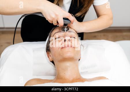 La cliente profite du traitement de rajeunissement facial RF Lifting dans un cadre de spa apaisant, mettant en évidence l'innovation en matière de soins de la peau et les soins professionnels pour vous Banque D'Images