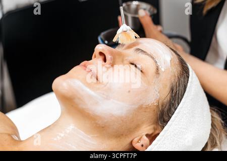 La cliente profite du traitement de rajeunissement facial RF lifting dans un environnement de spa serein, mettant en évidence l'application de soins de la peau et l'ambiance apaisante pour Banque D'Images
