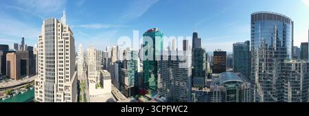 Vue aérienne de gratte-ciel attrapant la lumière du matin, leurs façades en verre reflétant le ciel bleu clair, autour de la rivière, Chicago, Illinois, USA. Banque D'Images