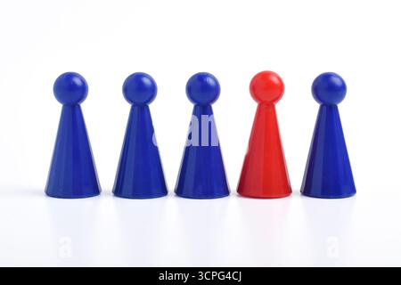 Figure rouge de jeu de plateau parmi les bleus sur fond blanc. Différence, individualité, unicité Banque D'Images