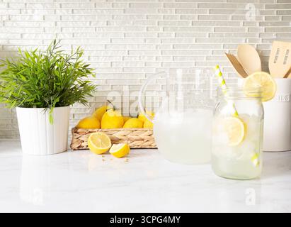 Cuisine lumineuse avec citrons et limonade dans un pichet en verre et pot maçon Banque D'Images