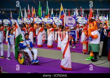 New Delhi, New Delhi, INDE. 25 septembre 2025. Lors du défilé des Nations lors de la cérémonie d'ouverture des Championnats du monde IndianOil New Delhi 2025 de para Athlétisme au Jawaharlal Nehru Stadium, Delhi, un athlète en fauteuil roulant de l'Inde porte le drapeau national tandis qu'un volontaire mène avec l'affiche IND. La mascotte colorée se tient à côté d'un extincteur alors que des volontaires tenant des pancartes pour le Cameroun, le Chili, la Colombie, Hong Kong (Chine) et le Mexique s'alignent en arrière-plan. (Crédit image : © Ankit Roy Majumder/ZUMA Press Wire) USAGE ÉDITORIAL SEULEMENT ! Non destiné à UN USAGE commercial ! Banque D'Images