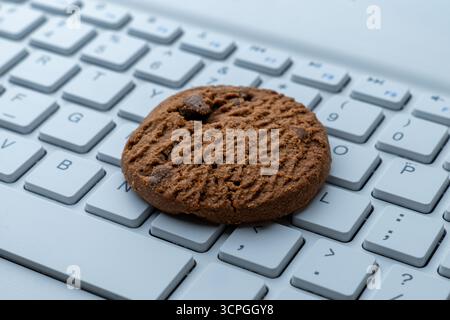 Gros plan d'un cookie sur un clavier d'ordinateur. Cookies Internet, technologie et concepts de confidentialité en ligne. Banque D'Images