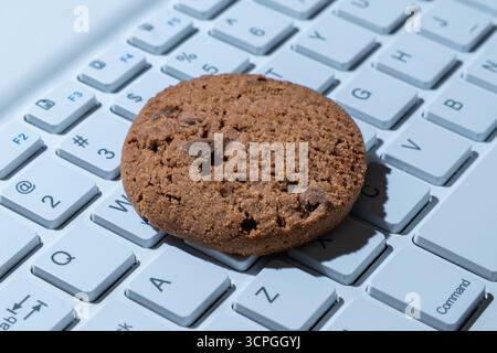 Gros plan d'un cookie sur un clavier d'ordinateur. Cookies Internet, technologie et concepts de confidentialité en ligne. Banque D'Images