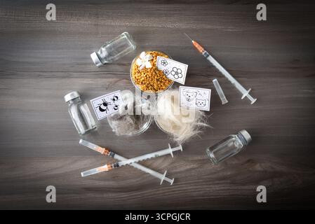 Détail de fond avec divers allergènes tels que les acariens, le pollen et les poils d'animaux et les squames sur une table en bois au centre avec plusieurs doses de va Banque D'Images
