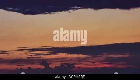 Un ciel magique au coucher du soleil avec de doux nuages brillants dans des tons chauds de rose, orange et violet, évoquant la paix et l'émerveillement. Banque D'Images