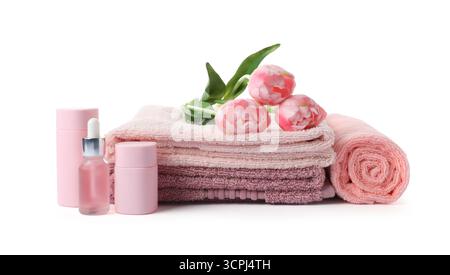 Pile de serviettes éponge fraîches, de produits cosmétiques et de fleurs isolées sur blanc Banque D'Images