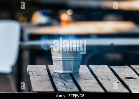 Fumée s'élevant d'un cendrier sur une table Banque D'Images