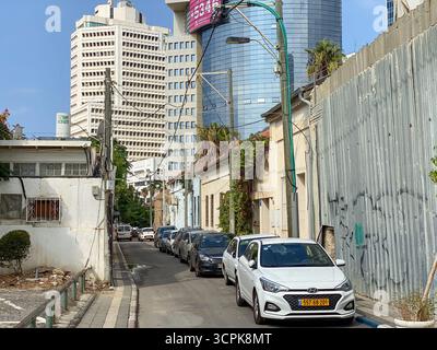 Jérusalem, Israël - 28 octobre 2019 : vue sur une rue étroite bordée de voitures stationnées, juxtaposée contre les gratte-ciel modernes percant le ciel bleu vif. Banque D'Images