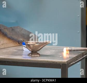 L'artiste souffleur de verre façonne le verre fondu en un objet décoratif lors d'un atelier dans un cadre de studio Banque D'Images