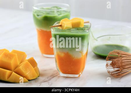 Latte Matcha mangue glacée en verre sur table blanche Banque D'Images
