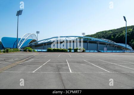 Un parking vide en face du Kirklees Stadium, Huddersfield, présentant son toit bleu distinctif et ses projecteurs sous un ciel dégagé. Banque D'Images