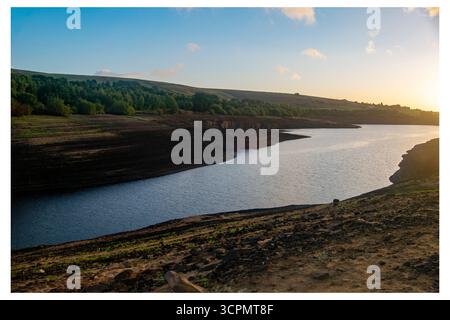 La lumière du matin illumine le réservoir Baitings considérablement épuisé, révélant de vastes étendues de terres exposées en raison de la sécheresse persistante. Banque D'Images