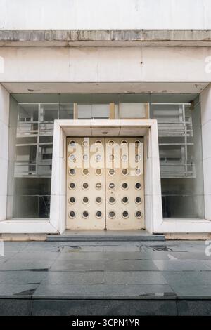 Porte moderniste frappante avec fenêtres de forme circulaire et béton brutaliste sur Une façade de bâtiment public. Architecture abstraite, géométrique, entrée Banque D'Images