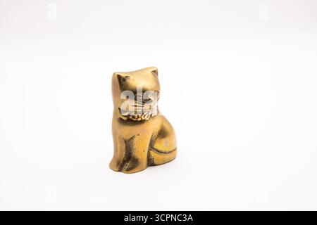 Gros plan d'une petite figurine de chat en laiton, ornement métallique décoratif isolé sur blanc. Banque D'Images