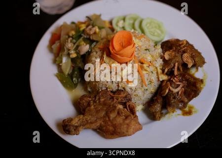 Repas traditionnel de riz frit d'Asie du Sud-est (Nasi Goreng) avec poulet frit et légumes sautés Banque D'Images