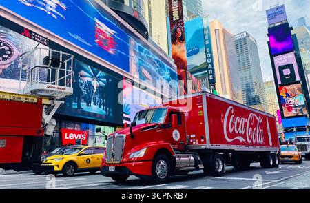 Camion Coca-Cola conduisant à travers Times Square avec Billboards lumineux et la vie urbaine Banque D'Images