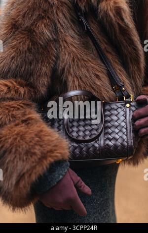 Détails à la mode d'un manteau de fourrure, gants en daim, sac à main marron tendance en cuir tissé, vêtements automne-hiver et tenue de rue pour femmes Banque D'Images