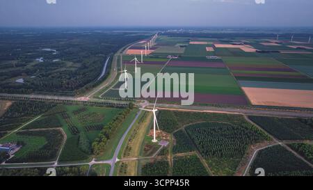 Moulins à vent le long des champs agricoles, après le coucher du soleil. Vue drone du paysage rural du soir avec parc éolien aux pays-Bas. Énergie alternative, Green ener Banque D'Images