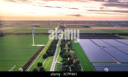 Vue drone du paysage rural du soir avec centrale éolienne et solaire aux pays-Bas. Moulins à vent le long des champs agricoles après le coucher du soleil. Alternative en Banque D'Images