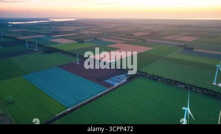 Moulins à vent le long des champs agricoles, après le coucher du soleil. Vue drone du paysage rural du soir avec parc éolien aux pays-Bas. Énergie alternative, Green ener Banque D'Images