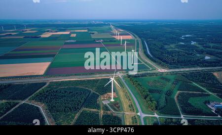Moulins à vent le long des champs agricoles, après le coucher du soleil. Vue drone du paysage rural du soir avec parc éolien aux pays-Bas. Énergie alternative, Green ener Banque D'Images