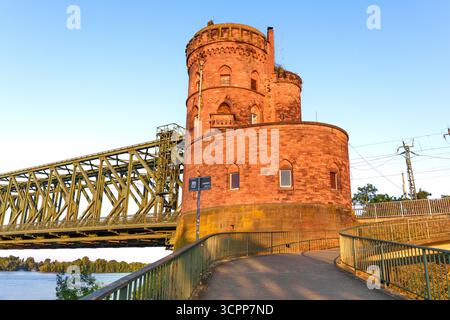 Mayence, Allemagne - 19 juin 2025 : tour historique de la forteresse en pierre à Mayence, Allemagne se dresse à côté d'un pont ferroviaire sur la rivière, illuminé par le soleil chaud Banque D'Images