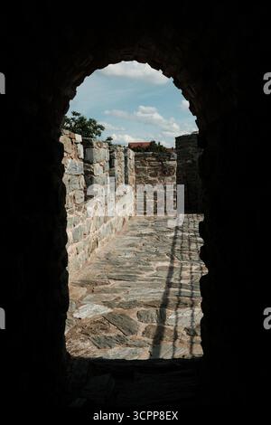 La lumière du soleil pénètre par un passage en pierre voûté à la forteresse de Ram, révélant un chemin le long du mur défensif. Une destination touristique populaire. Banque D'Images