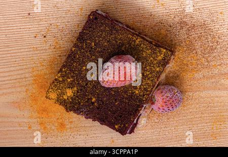 Une vue rapprochée d'un brownie fudgy. Sa texture humide et sa présentation alléchante. Un browni au chocolat décadent avec des fraises fraîches. Vue de dessus. Banque D'Images