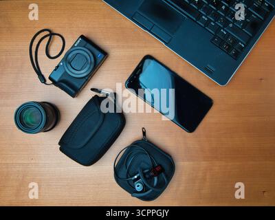 Espace de travail créatif Overall Tech Gear - pose verticale d'un appareil photo, d'un objectif, d'un smartphone, d'écouteurs et d'un ordinateur portable sur un bureau en bois. Concept pour photograp Banque D'Images