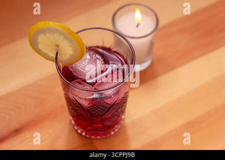 Spritzer au vin rouge avec citron andice, réglage aux chandelles. Vin rouge espagnol spritzer avec glace et garniture de tranche de citron. L'image transmet un rafraîchissement Banque D'Images