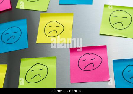 Allemagne - 27 septembre 2025 : de nombreux smileys tristes sur des morceaux de papier symbolisent une culture ratée du feedback et de la critique dans l'environnement professionnel. *** Viele traurige Smileys auf Zetteln stehen sinnbildlich für eine gescheiterte Feedback- oder Kritik-Kultur im beruflichen Umfeld. Banque D'Images