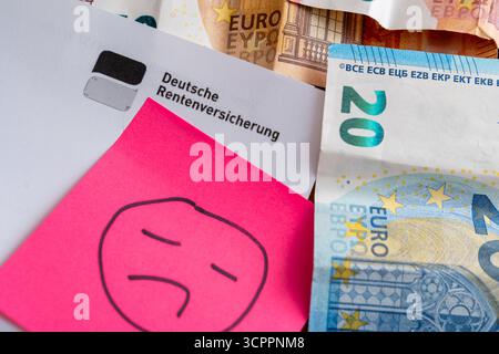 Allemagne - 27 septembre 2025 : une lettre de la Caisse allemande d'assurance pension contenant des billets en euros et un triste smiley symbolise les inquiétudes de nombreuses personnes concernant les périodes sombres pour les pensions, les paiements de pension incertains et la pauvreté dans la vieillesse en Allemagne. *** Ein Brief der Deutschen Rentenversicherung mit Euroscheinen und einem traurigen Smiley symbolisiert die Sorgen vieler Menschen über miese Zeiten für die rente, unsichere Rentenzahlungen und Altersarmut in Deutschland. Banque D'Images