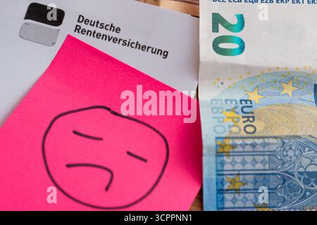 Allemagne - 27 septembre 2025 : une lettre de la Caisse allemande d'assurance pension contenant des billets en euros et un triste smiley symbolise les inquiétudes de nombreuses personnes concernant les périodes sombres pour les pensions, les paiements de pension incertains et la pauvreté dans la vieillesse en Allemagne. *** Ein Brief der Deutschen Rentenversicherung mit Euroscheinen und einem traurigen Smiley symbolisiert die Sorgen vieler Menschen über miese Zeiten für die rente, unsichere Rentenzahlungen und Altersarmut in Deutschland. Banque D'Images
