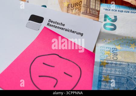 Allemagne - 27 septembre 2025 : une lettre de la Caisse allemande d'assurance pension contenant des billets en euros et un triste smiley symbolise les inquiétudes de nombreuses personnes concernant les périodes sombres pour les pensions, les paiements de pension incertains et la pauvreté dans la vieillesse en Allemagne. *** Ein Brief der Deutschen Rentenversicherung mit Euroscheinen und einem traurigen Smiley symbolisiert die Sorgen vieler Menschen über miese Zeiten für die rente, unsichere Rentenzahlungen und Altersarmut in Deutschland. Banque D'Images