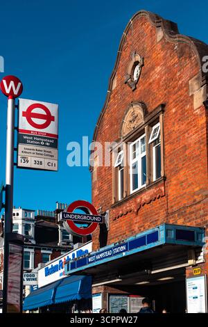 Panneau d'arrêt de bus de la station de métro West Hampstead contre le front de la station, Londres, Angleterre, Royaume-Uni. Banque D'Images
