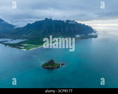Vue aérienne de l'endroit où la chaîne de montagnes accidentée Ko'olau rencontre les eaux turquoises sereines, avec l'île Mokolii debout de la garde, Honolulu, Hawaï, États-Unis. Banque D'Images