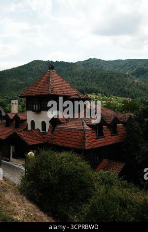 Grande maison traditionnelle avec toit de tuiles rouges à Mokra Gora, en Serbie, entourée de collines boisées. Banque D'Images